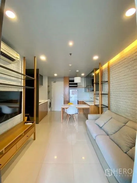 Condominium for rent in Chatuchak, Bangkok - Open-plan living area showing sofa, TV console, shelving and bright tiled floors.