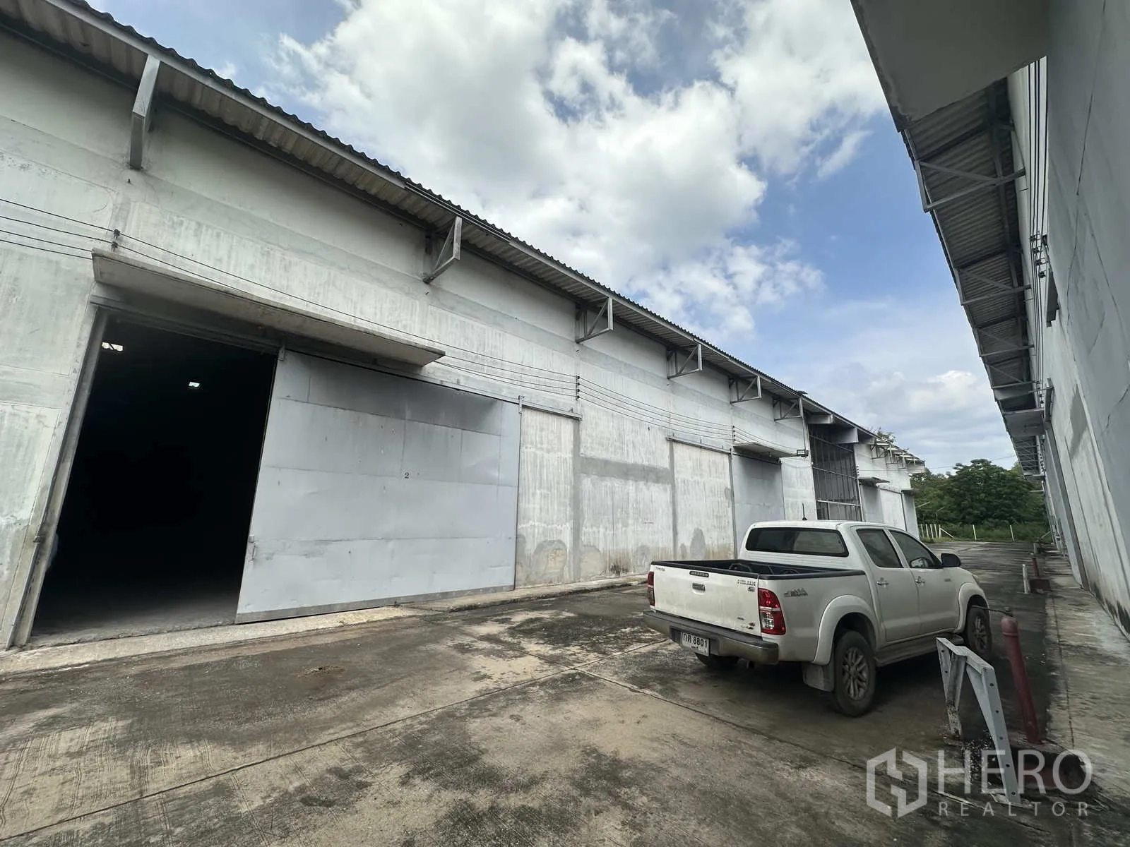 Warehouse for rent in Phra Nakhon Si Ayutthaya - Row of warehouse units with open door and parked pickup truck.