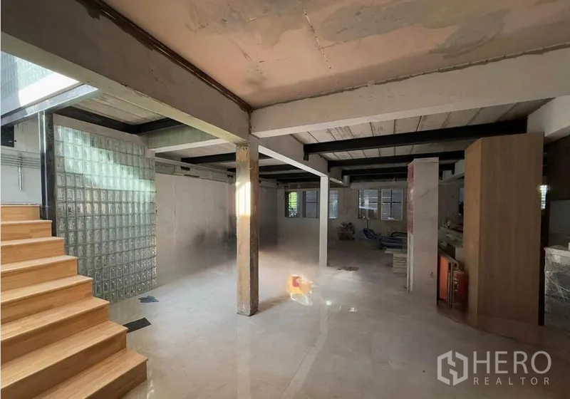 Office Space for rent in Khlong Toei, Bangkok - Open-plan office interior with exposed beams, glass-block partition, polished tile floors, and wooden staircase lit by natural light.