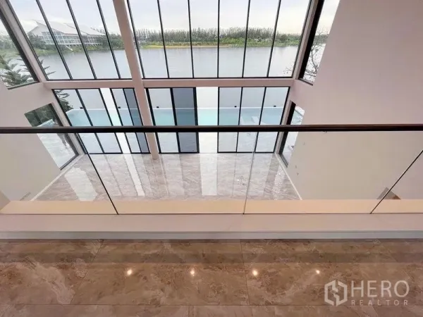 Detached House for sale in Bang Phli, Samut Prakan - Mezzanine outlook over glossy marble floors and two-story glazing facing the lake.
