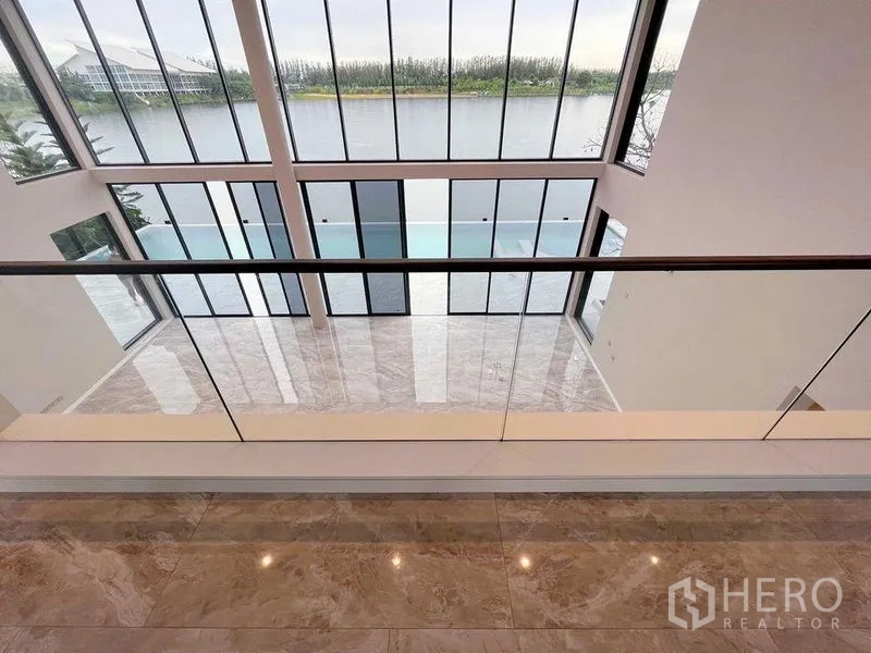 Detached House for sale in Bang Phli, Samut Prakan - Mezzanine outlook over glossy marble floors and two-story glazing facing the lake.