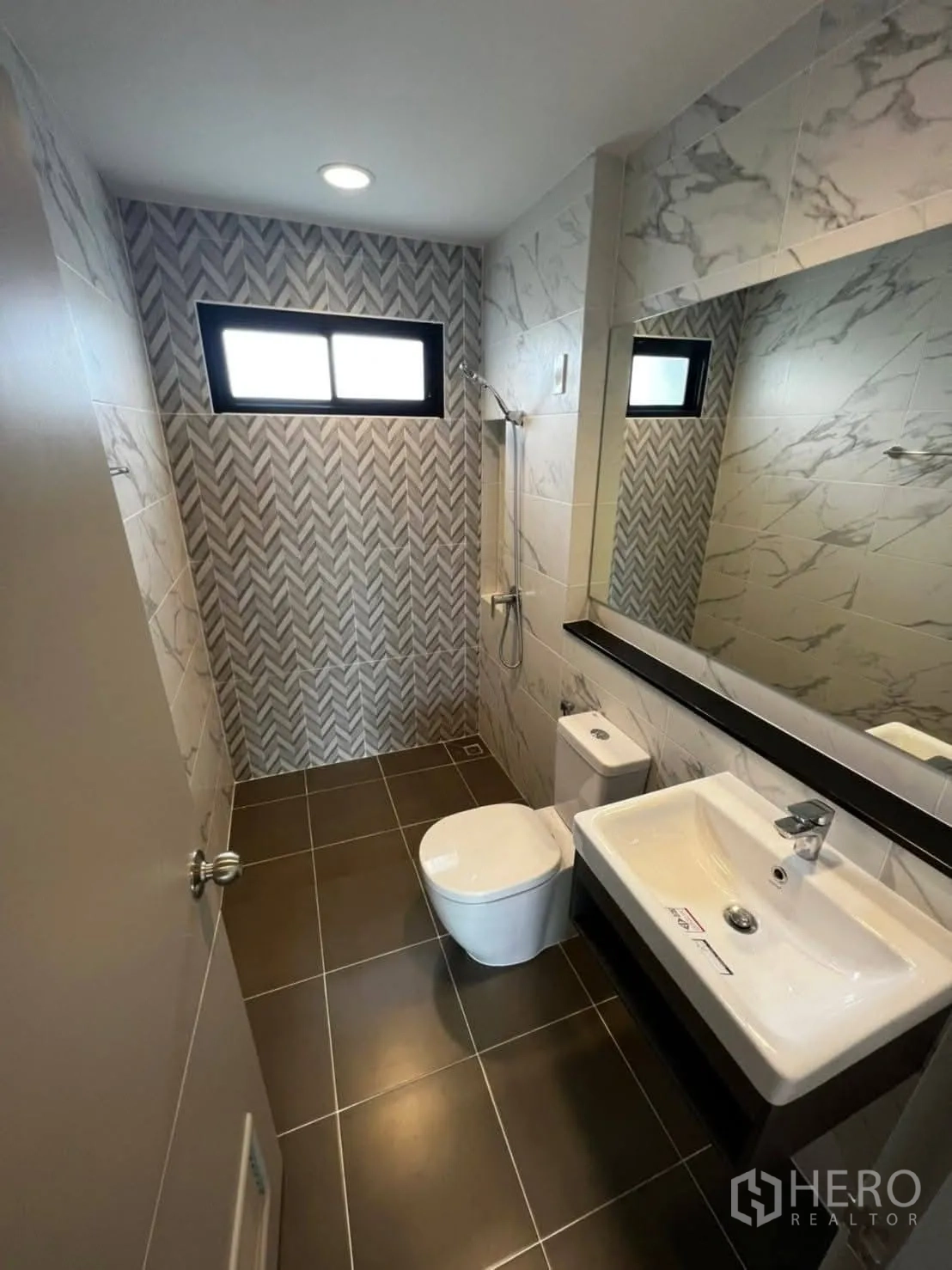 Townhouse for rent in Bang Khen, Bangkok - Contemporary bathroom with patterned feature wall, shower, mirror, and white fixtures.
