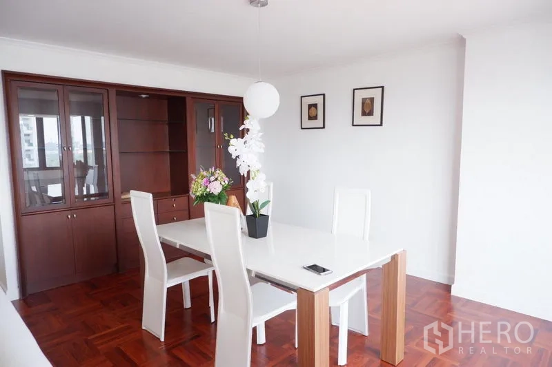 Condominium for rent in Khlong Toei, Bangkok - Dining space with built-in wooden cabinet, modern pendant light and white table set.