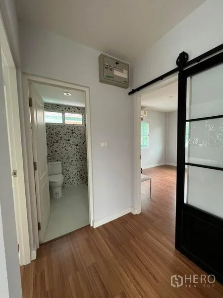 Detached House for sale in Bang Kruai, Nonthaburi - Upstairs hallway with sliding door, wood floors and entrance to a bathroom.