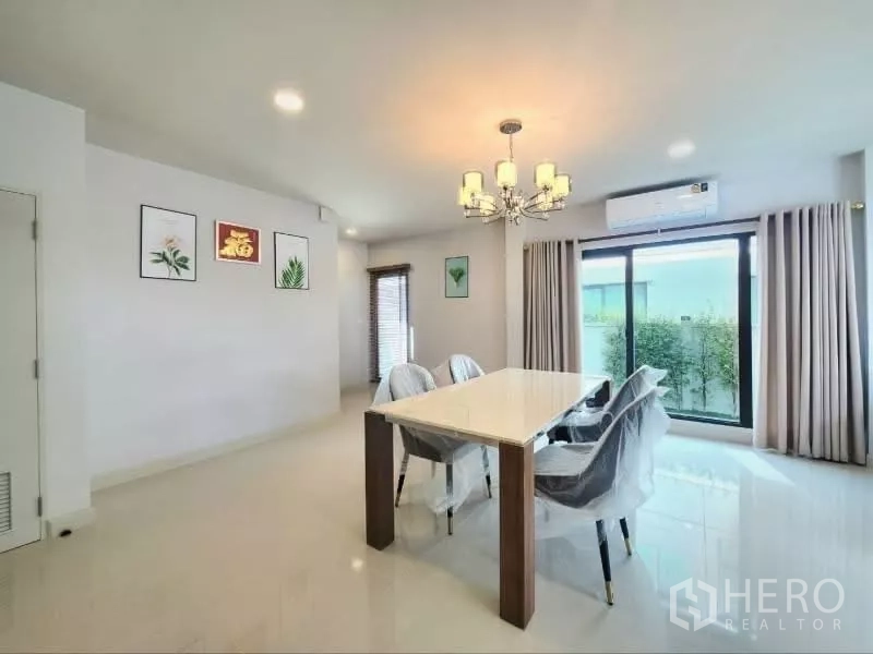 Detached House for rent in Bang Phli, Samut Prakan - Dining area with six-seat table, chandelier and sliding doors to the garden.