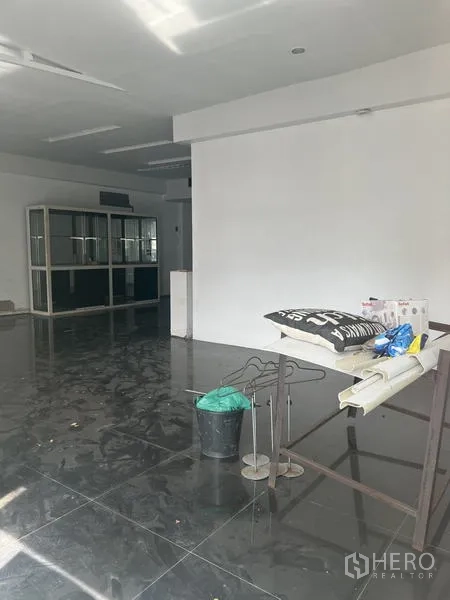 Retail Space for rent in Watthana, Bangkok - Close-up of shop interior showing fixtures and cleaning tools on reflective black tiles.