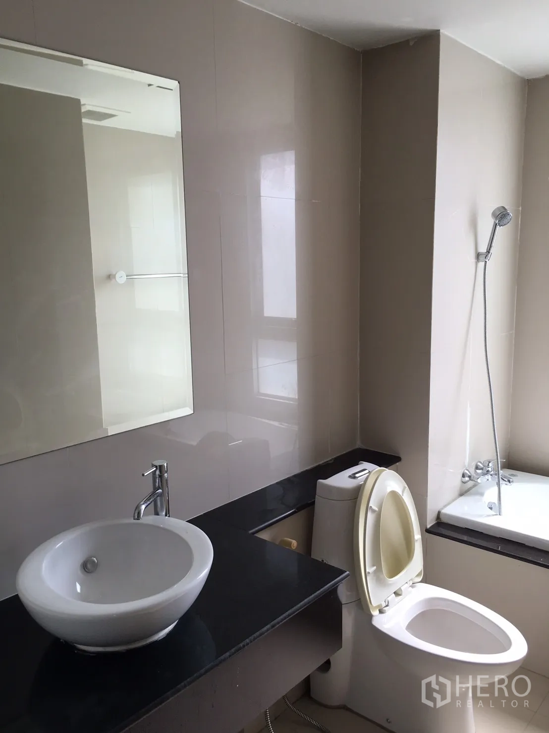 Condominium for rent or sale in Khlong Toei, Bangkok - Bathroom with vessel sink on black countertop, toilet and a bathtub with shower.