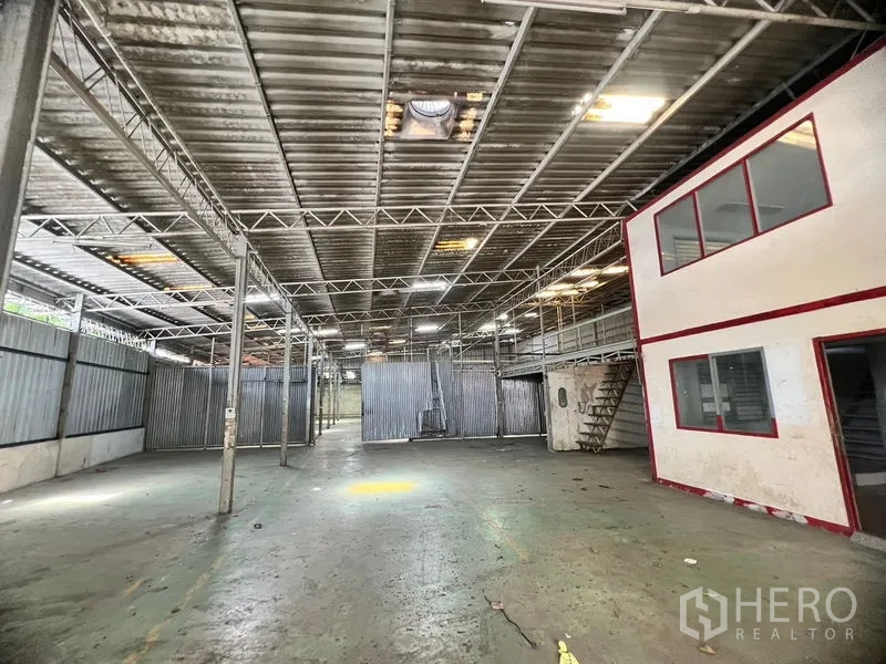 Warehouse for rent in Suan Luang, Bangkok - Main warehouse hall featuring red‑trimmed office block and partitioned storage zones.