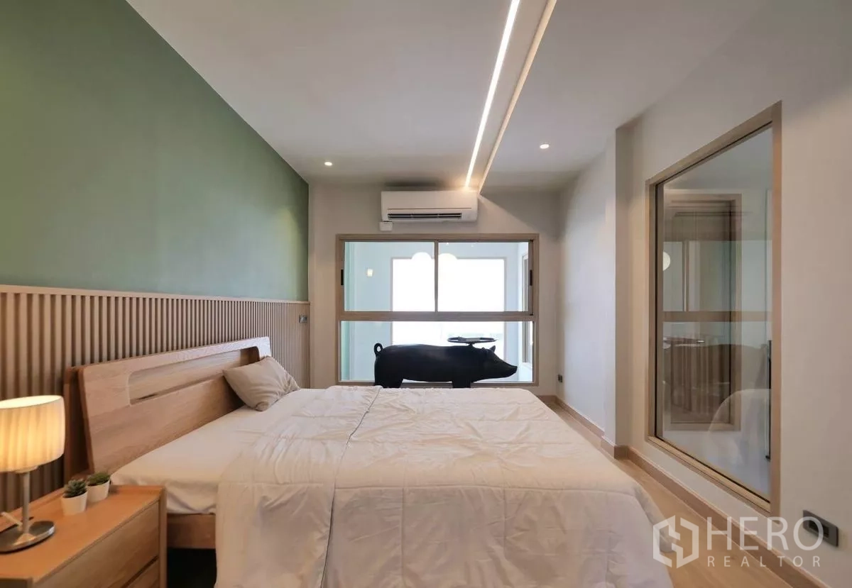 联排别墅 出租在Watthana, Bangkok - 温馨卧室，绿色背景墙、木床头与室内窗。