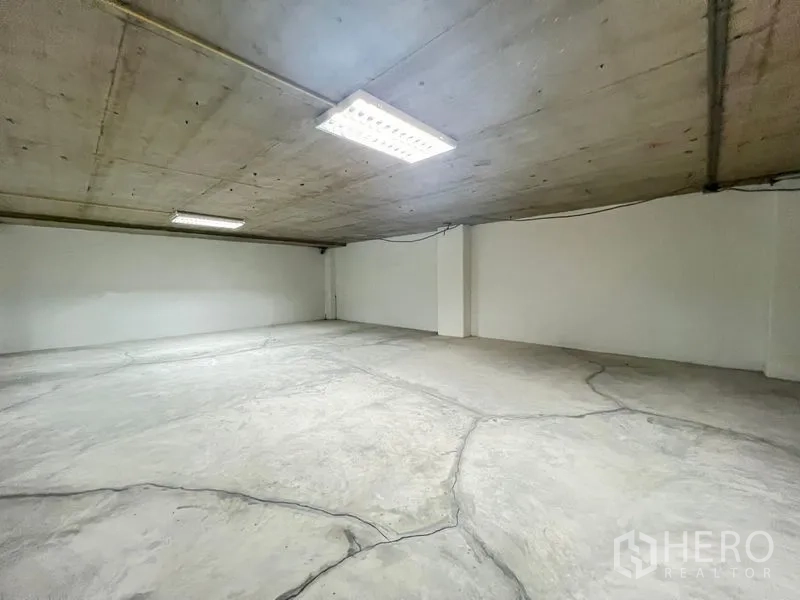 Office Space for rent - Large empty office room with concrete floor, exposed ceiling and fluorescent lights.