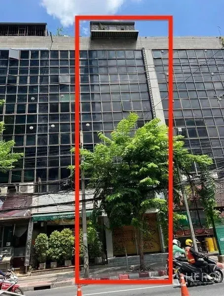 Shophouse for rent in Bang Rak, Bangkok - Street-front shophouse within a glass-clad commercial block in Bang Rak, with trees and a ground-floor shopfront.
