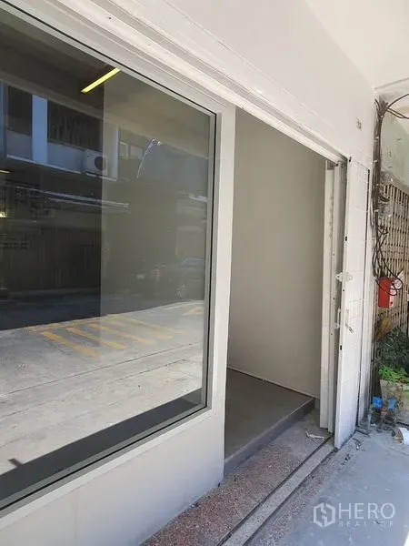 Shophouse for rent in Phra Khanong, Bangkok - Street-facing shop entrance with a large glass display window and sliding door.