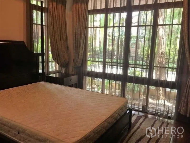 Detached House for sale - Bedroom with tall windows and garden view, dark wood furniture.