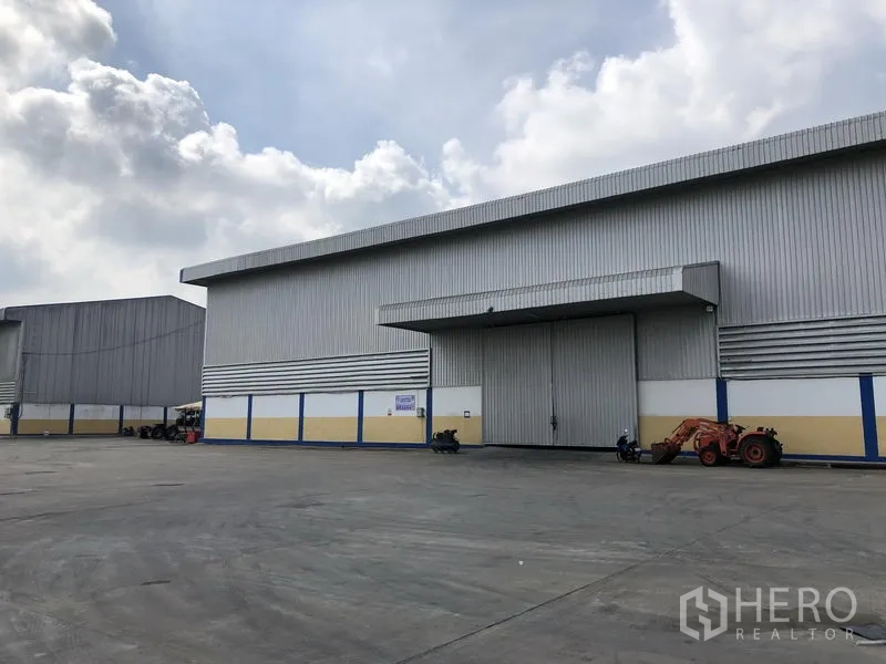 Warehouse for rent in Phra Nakhon Si Ayutthaya - Front of a large warehouse with sliding door and canopy, offering ample truck maneuvering space.