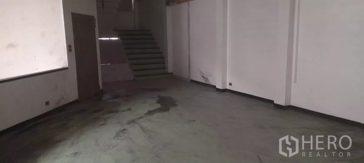 Retail Space for rent in Bang Na, Bangkok - Empty retail floor with concrete surface, white walls, and stairs leading to upper levels, ready for fit-out.