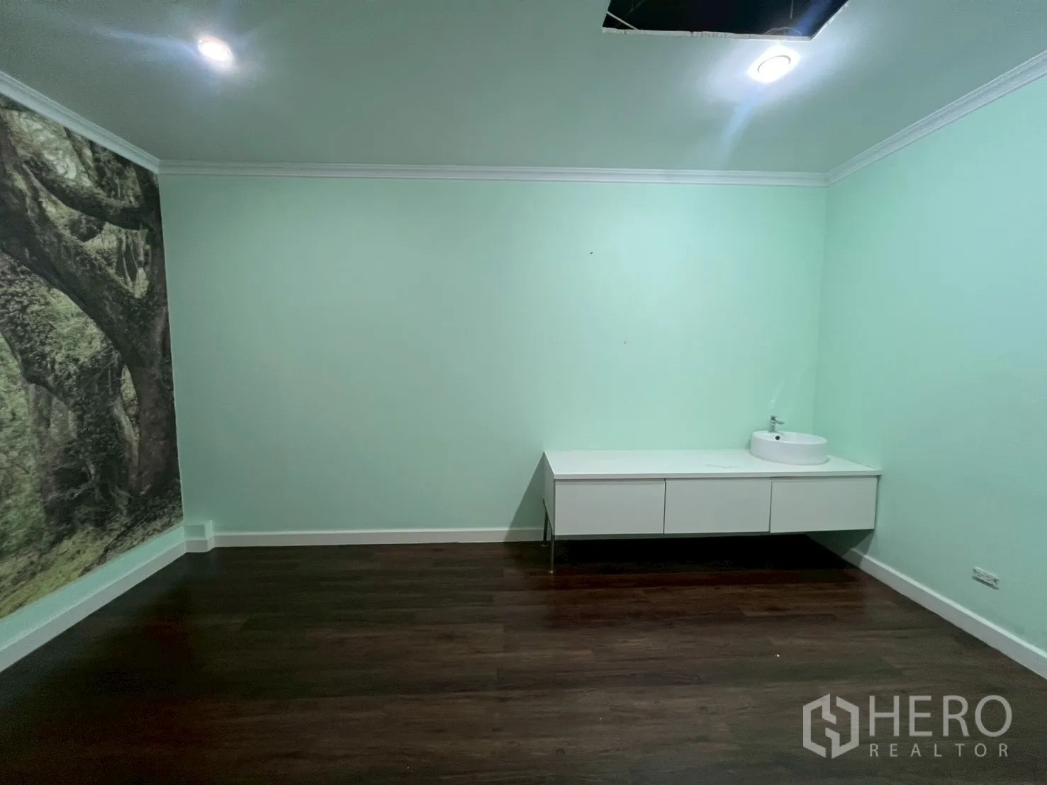 Office Space for rent in Watthana, Bangkok - Private room with mint-green walls, wood floor and white vanity with round basin, ideal for clinic treatment room.
