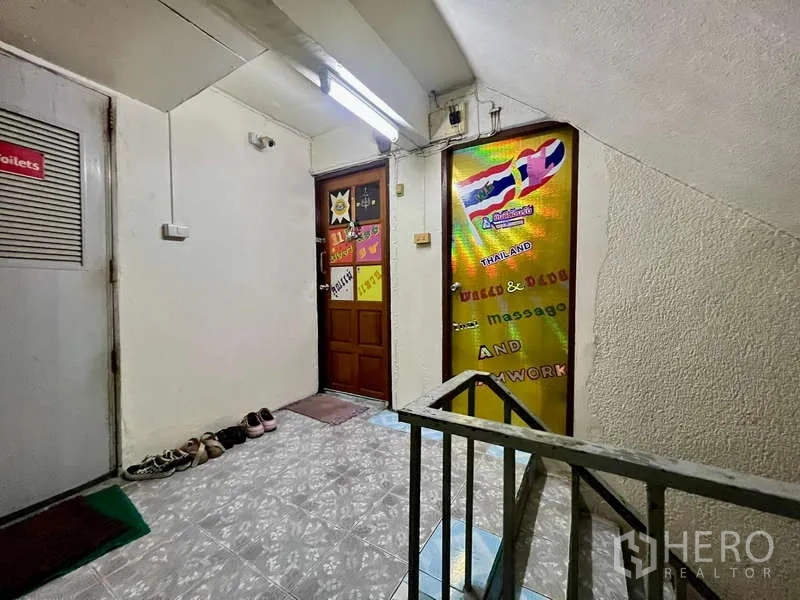 Shophouse for rent in Khlong Toei, Bangkok - Upper-floor corridor with fluorescent lighting, doors and signage beside the stairwell in the shophouse.