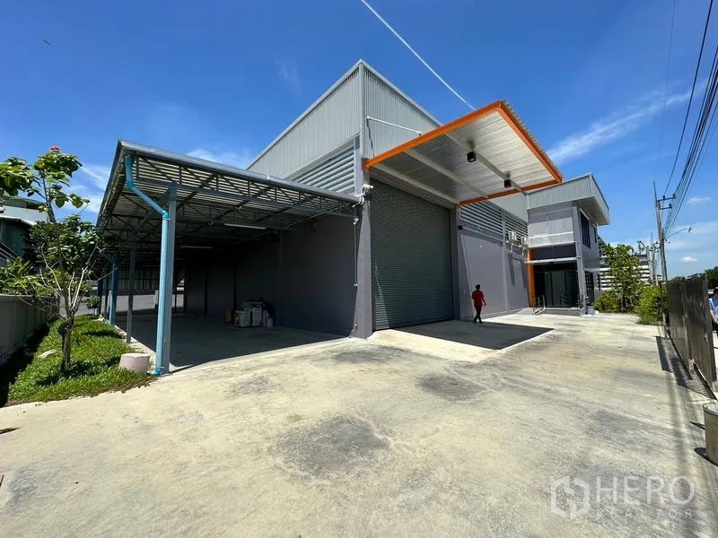 Factory for rent or sale in Lam Luk Ka, Pathum Thani - Modern factory exterior in Lam Luk Ka with high roller shutter, covered loading bay and wide concrete yard.