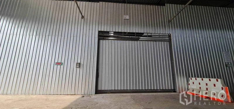 Warehouse for rent in Pak Kret, Nonthaburi - Large corrugated metal sliding door at the warehouse entrance with a loading bay.