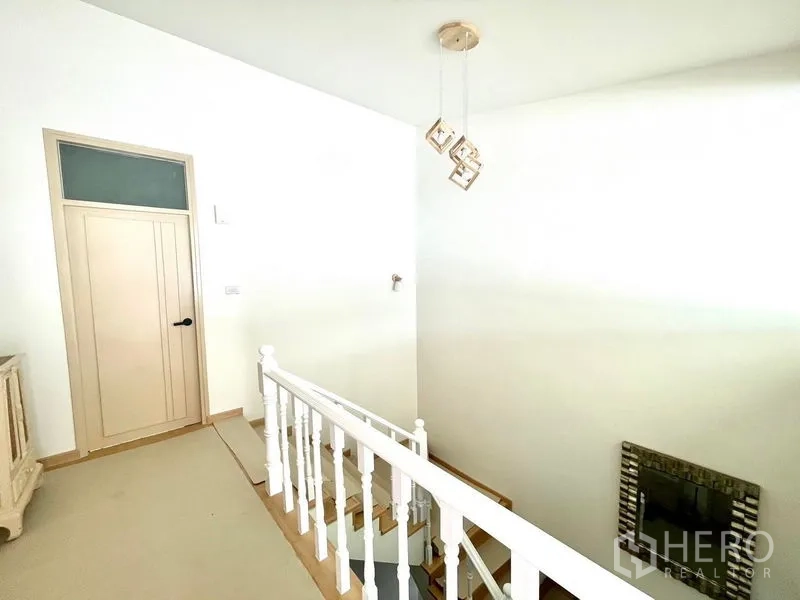 Townhouse for rent in Khlong Toei, Bangkok - Stair landing with white balustrade and cubic pendant light.