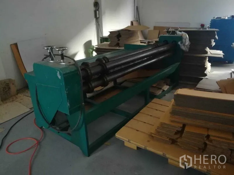 Factory for sale in Bang Len, Nakhon Pathom - Green heavy-duty roller press with piles of cardboard in the workshop.