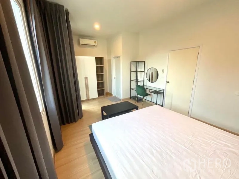 Townhouse for rent in Bang Phli, Samut Prakan - Airy bedroom with white wardrobe, study desk and dark blackout curtains.