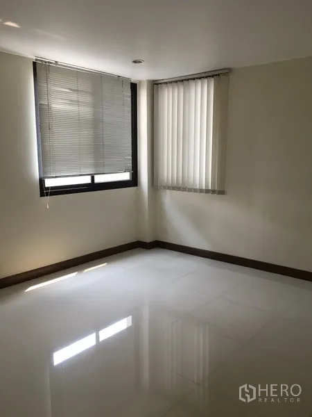 Home Office for rent in Bang Rak, Bangkok - Corner bedroom or workspace with two windows, venetian blinds and polished floors.