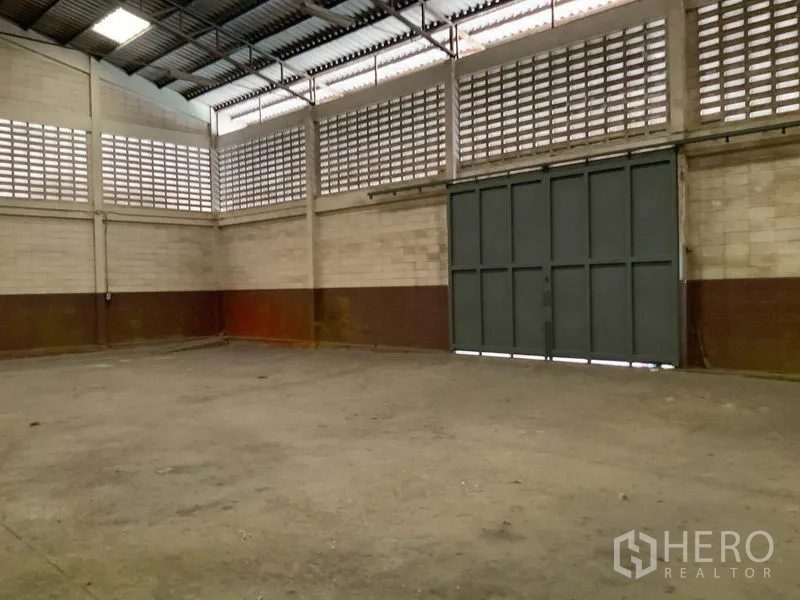 Warehouse for rent in Bang Kapi, Bangkok - Open concrete warehouse floor with tall steel doors suitable for truck access.