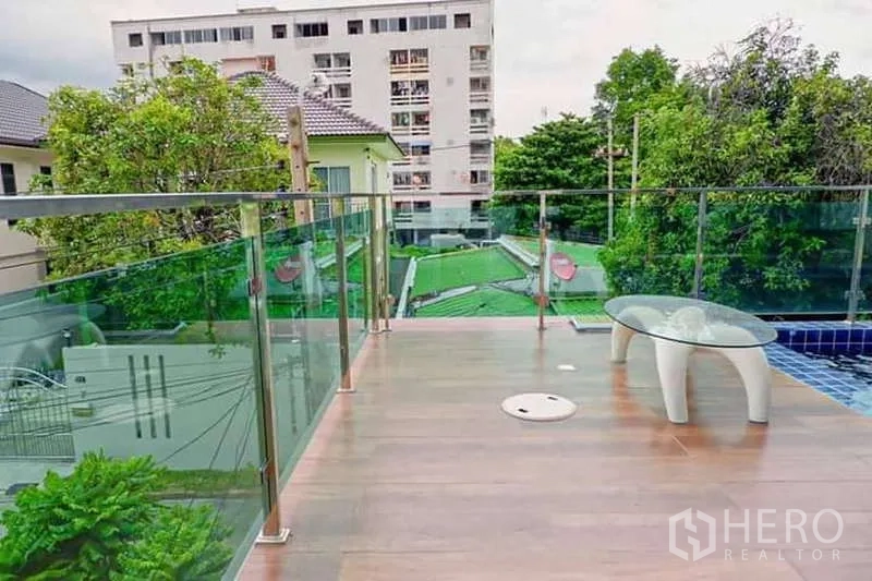 Detached House for sale in Lat Phrao, Bangkok - Poolside terrace with wood-look deck, glass balustrade, and neighborhood views.