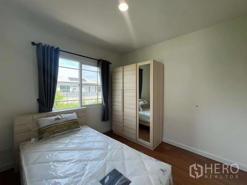 Detached House for rent in Bang Kapi, Bangkok - Sunny single bedroom with window views and a light wood wardrobe.