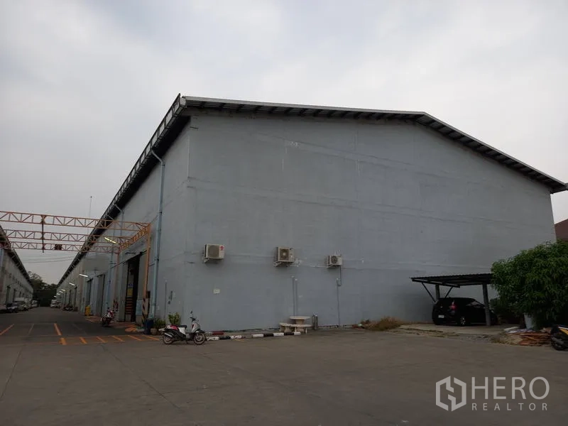 仓库 for rent in Mueang Pathum Thani, Pathum Thani - 仓库外立面带壁挂空调与带顶停车位。