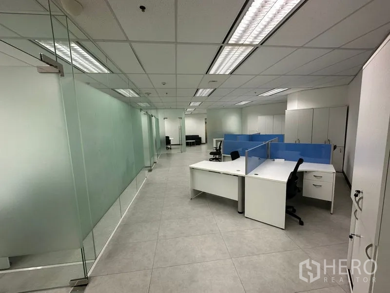 Office Space for rent - Glass-partitioned corridor leading to open workstations and a lounge area.