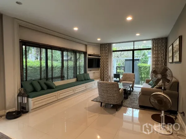Detached House for rent or sale in Bang Kapi, Bangkok - Spacious lounge with built-in TV wall, long bench seat and sliding glass doors to the garden.