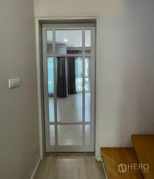Townhouse for sale in Suan Luang, Bangkok - Glass-panel sliding door at staircase landing leading to upper floor rooms.