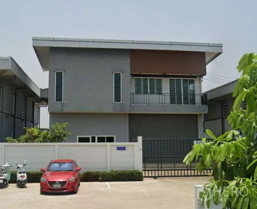 Factory for rent or sale in Ban Phaeo, Samut Sakhon - Two-storey mini factory with office, balcony and large roller shutter behind a gated parking area in Samut Sakhon