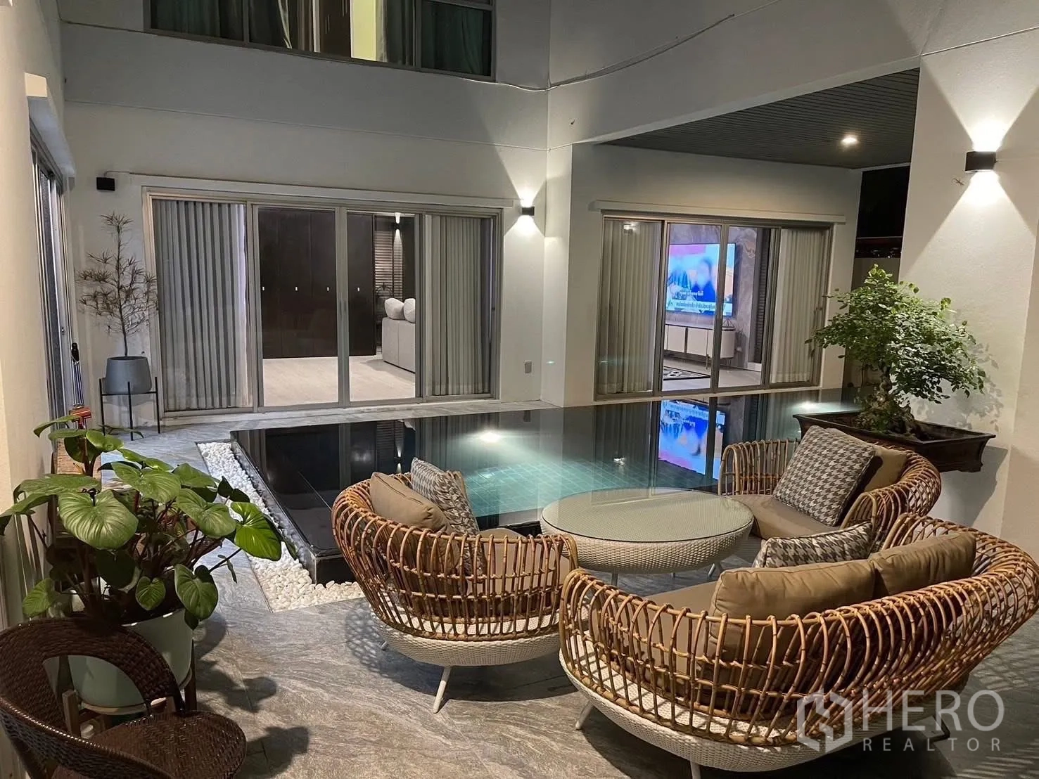 Detached House for rent in Suan Luang, Bangkok - Covered poolside patio with wicker seating illuminated at night.