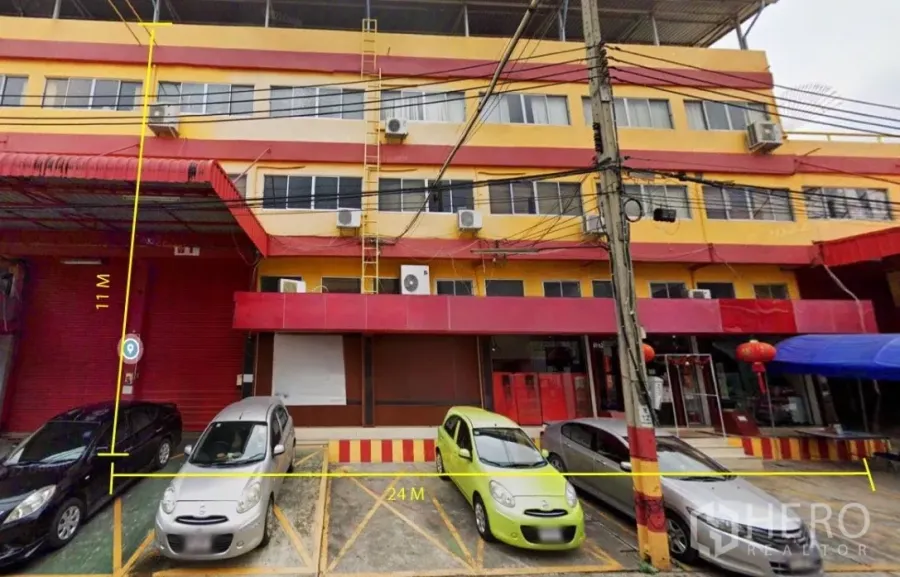 คลังสินค้า ให้เช่าในBang Phli, Samut Prakan - ด้านหน้าอาคารพาณิชย์สีแดงเหลือง มีที่จอดรถทำเครื่องหมายและหน้ากว้างพร้อมประตูม้วน