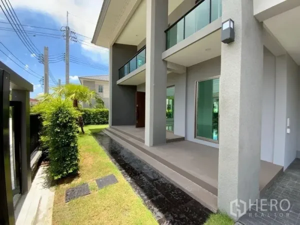 Townhouse for rent in Prawet, Bangkok - Front porch with tall columns, upper balcony and small lawn along the fence.