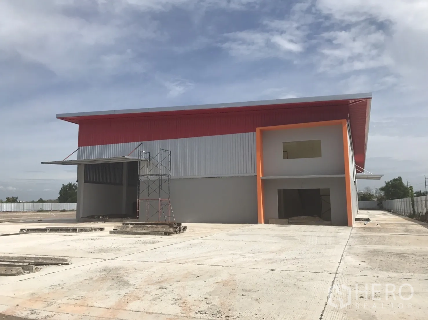 Warehouse for sale in Sai Noi, Nonthaburi - Front exterior of the warehouse with loading bay canopy, office block, and a wide concrete yard.
