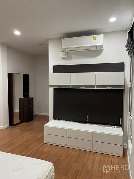 Detached House for rent in Bang Kapi, Bangkok - Modern wall unit with overhead cabinets and split air conditioner in a wood-floored bedroom.