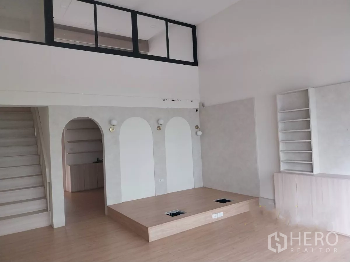 Retail Space for rent - Open-plan shop with raised display platform, arched niches, staircase and a mezzanine behind a glass partition.