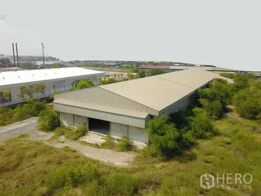 工厂 出售在Samut Prakan - 俯瞰金属屋顶的长条形工厂仓库，周围绿化与工业区景观