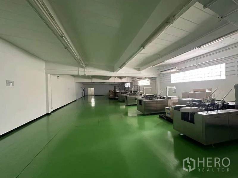 Warehouse for rent in Khlong Sam Wa, Bangkok - Clean production hall with green epoxy flooring, white walls and rows of machinery.