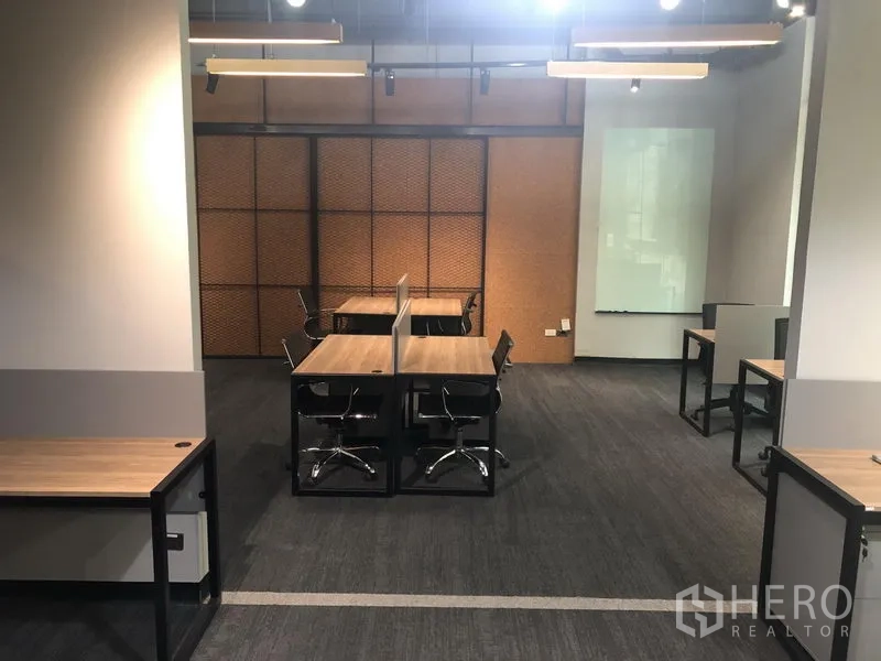 Office Space for rent in Watthana, Bangkok - Central bench desks with partitions, carpet flooring, glass whiteboard and industrial ceiling lights.
