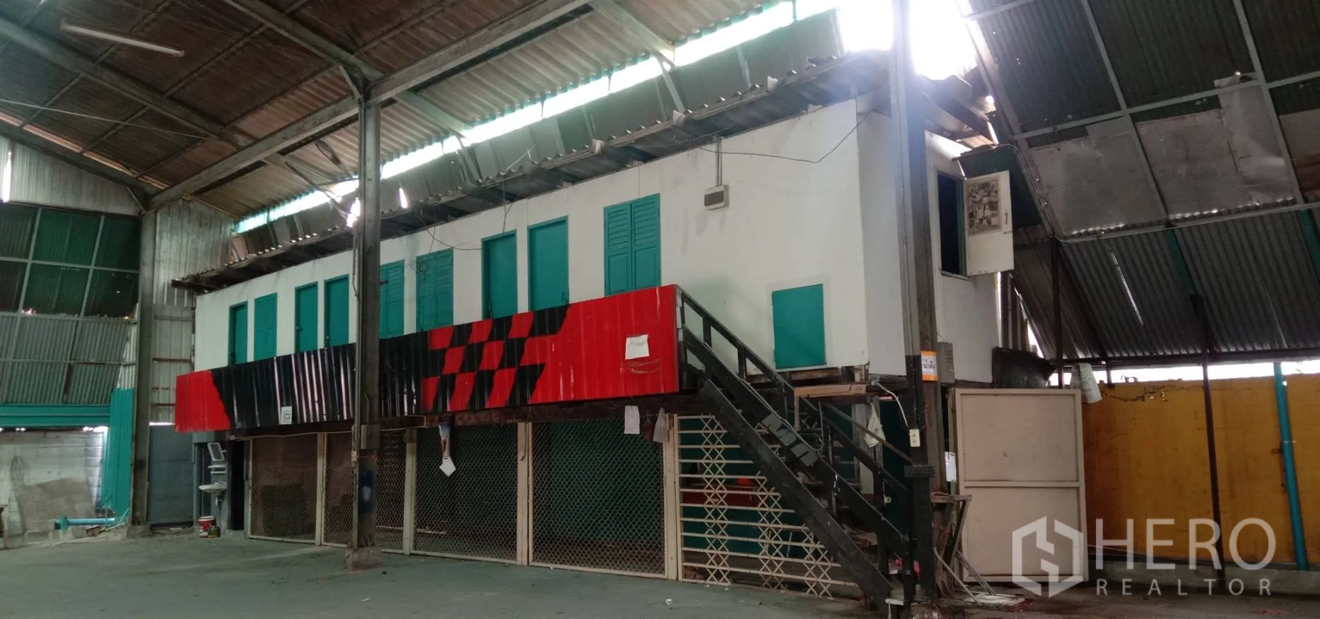 Warehouse for rent in Bueng Kum, Bangkok - Close view of the internal office structure with windows, yellow accent wall, wiring and translucent roof panels for natural light.