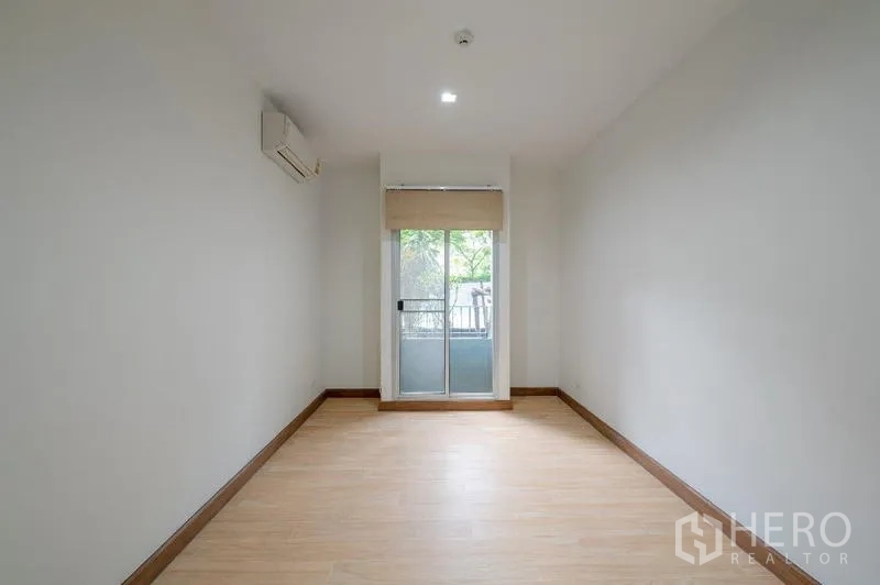Condominium for sale - Empty second bedroom with wood floors and sliding door to a small balcony.