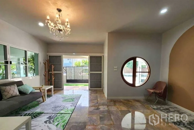Detached House for rent in Lam Luk Ka, Pathum Thani - Airy lounge with chandelier, round feature window and garden view.