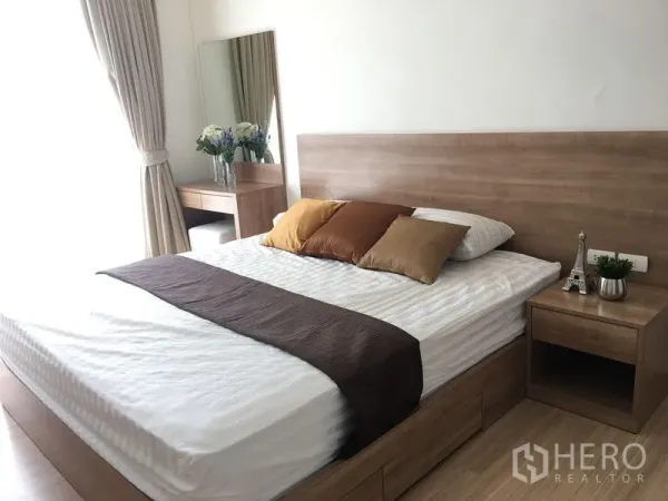 Condominium for rent in Khlong Toei, Bangkok - Bright master bedroom with wooden bed, bedside tables, dressing nook and soft curtains.