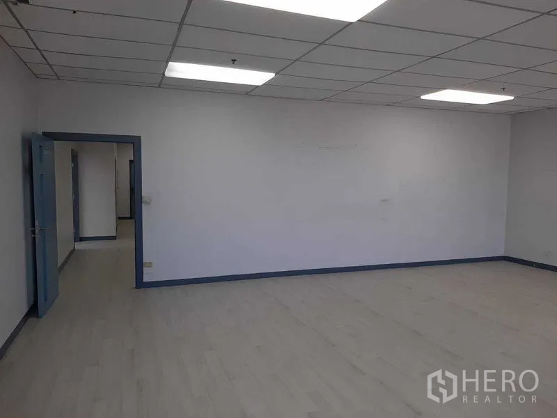 Office Space for rent in Khlong Toei, Bangkok - Large blank office room with blue door and ceiling grid lighting.