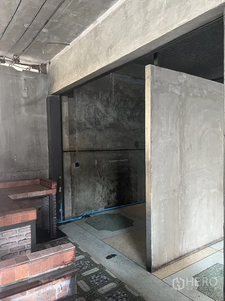 Retail Space for rent in Watthana, Bangkok - Covered side of the unit showing a brick bar, concrete walls, and terrazzo tiles.